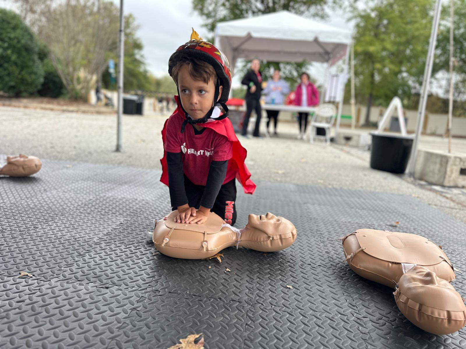 A child practicing CPR on a training manikin